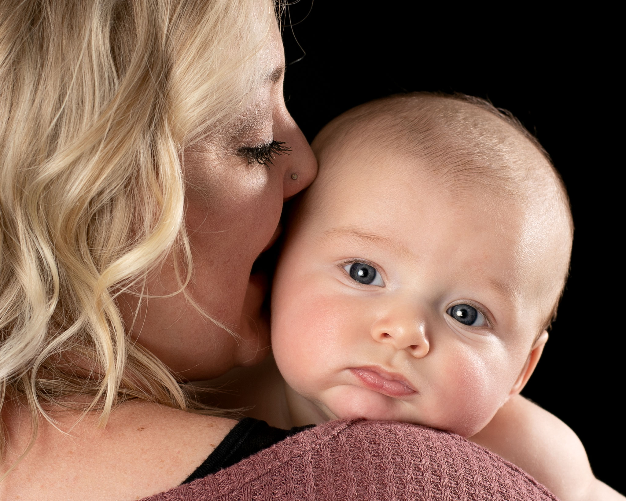 Joyful new mother kisses baby boy at Williams Photography Studio in Quincy, CA